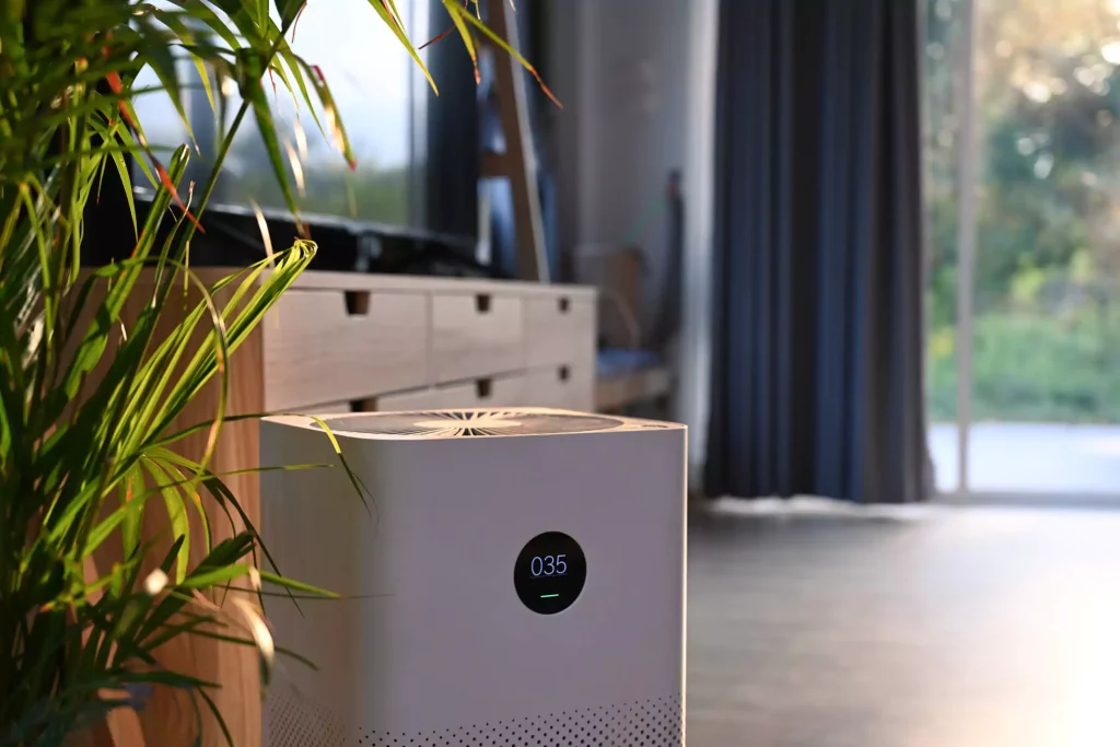 An air purifier in a room with a plant